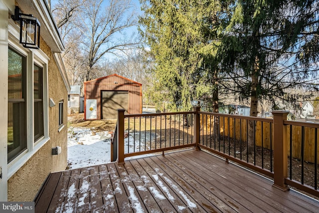 snow covered deck featuring a garage and an outdoor structure