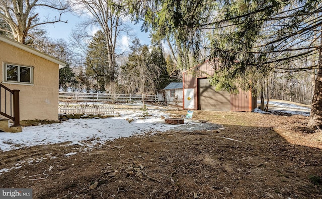 snowy yard with an outdoor fire pit and a shed