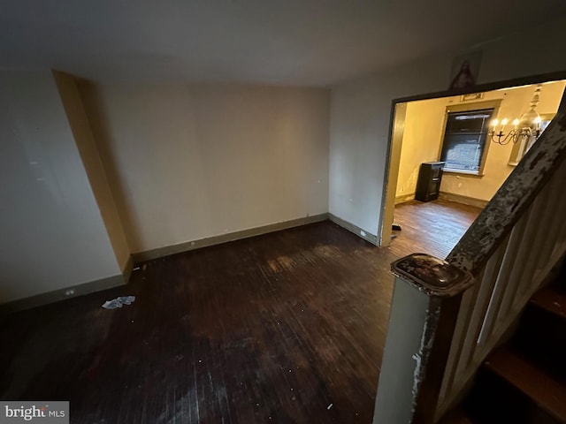 unfurnished room with a chandelier and dark hardwood / wood-style flooring