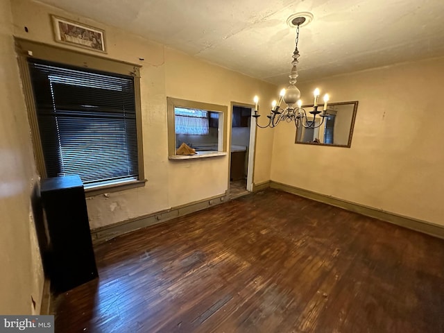 unfurnished dining area with dark hardwood / wood-style floors and a notable chandelier