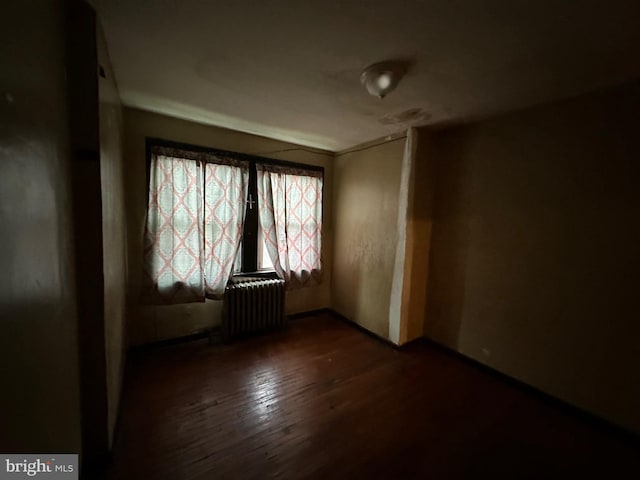 empty room featuring radiator heating unit and dark wood-type flooring