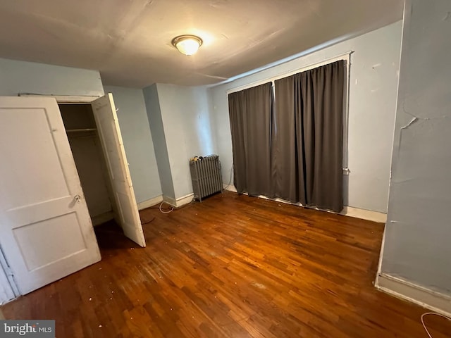 unfurnished bedroom featuring a closet, radiator, and dark wood-type flooring