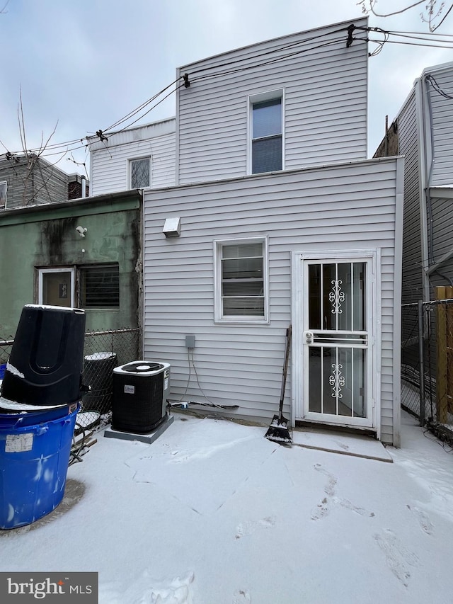 snow covered house featuring cooling unit