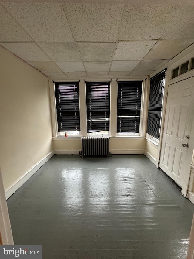 unfurnished room featuring radiator heating unit and a paneled ceiling