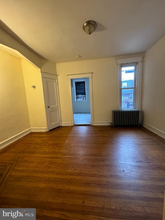 unfurnished room with radiator heating unit and dark hardwood / wood-style floors