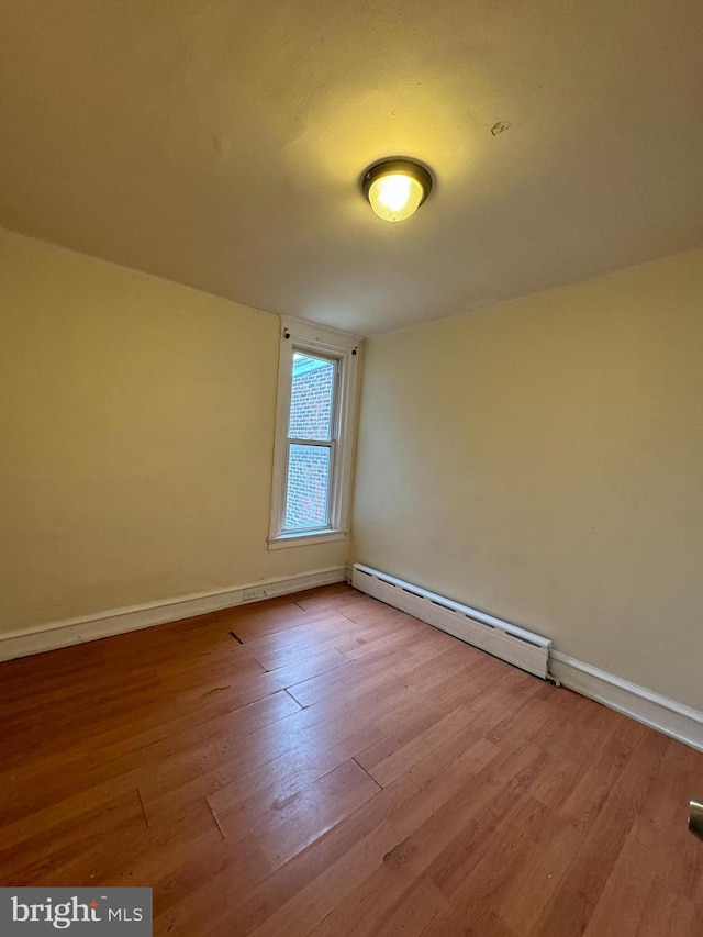 unfurnished room with light hardwood / wood-style floors and a baseboard heating unit