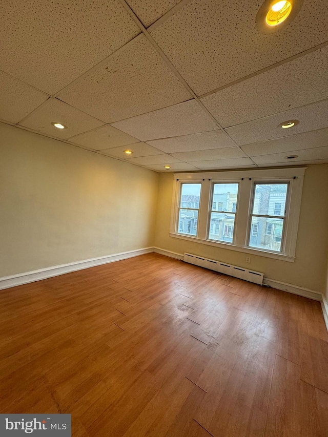 spare room with hardwood / wood-style floors, a paneled ceiling, a healthy amount of sunlight, and baseboard heating