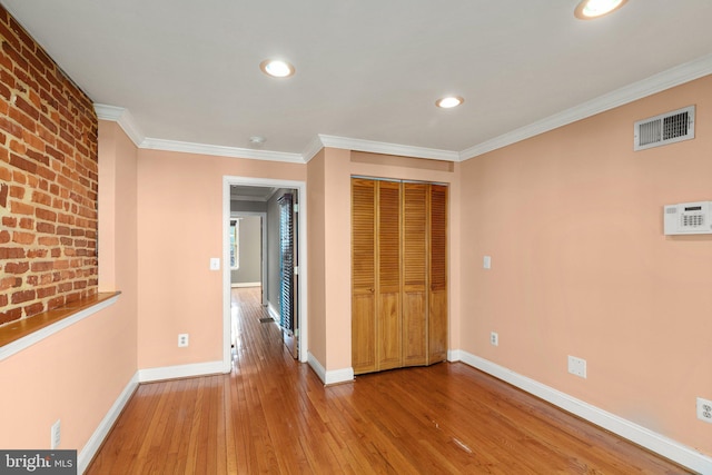 unfurnished bedroom featuring wood-type flooring, a closet, and crown molding