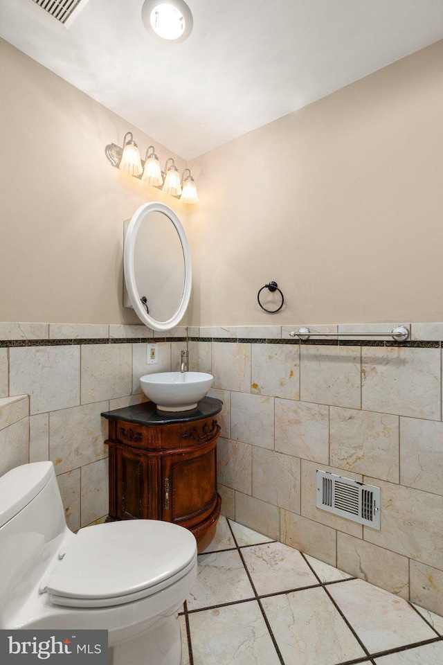 bathroom with tile patterned flooring, vanity, toilet, and tile walls