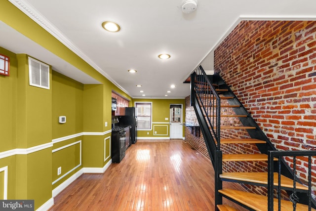 interior space featuring hardwood / wood-style floors, crown molding, and brick wall