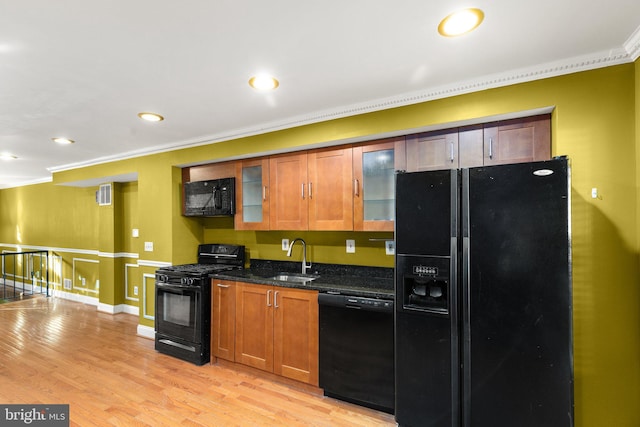 kitchen with black appliances, ornamental molding, sink, and dark stone counters