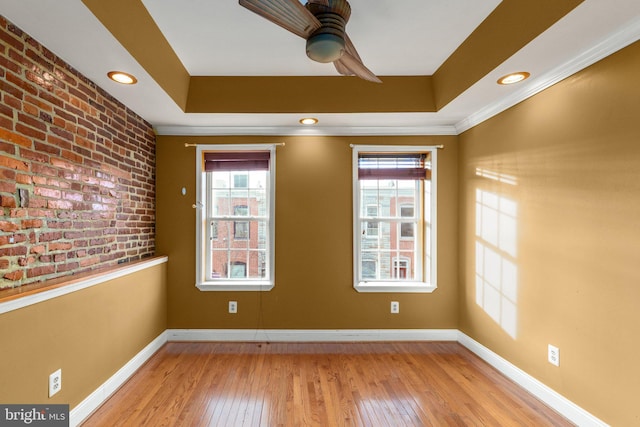 spare room with ceiling fan, a raised ceiling, crown molding, and light hardwood / wood-style flooring