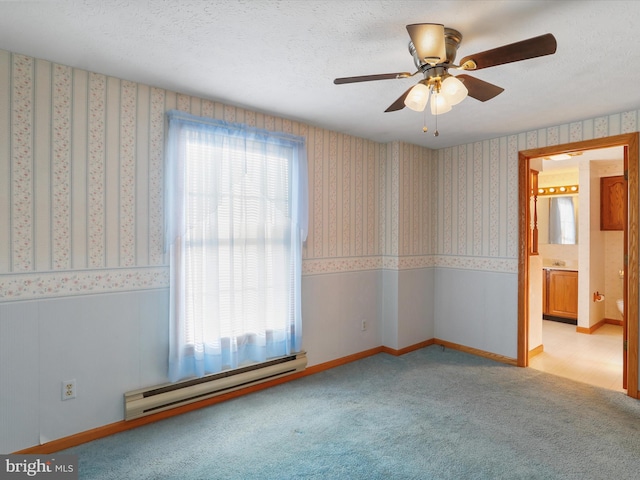 carpeted spare room with ceiling fan, a textured ceiling, and a baseboard heating unit