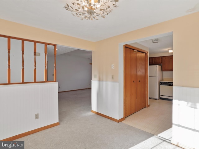 carpeted empty room featuring an inviting chandelier