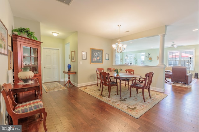 dining room with ceiling fan with notable chandelier, dark hardwood / wood-style floors, and decorative columns