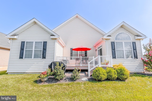 view of front of home with a deck and a front lawn