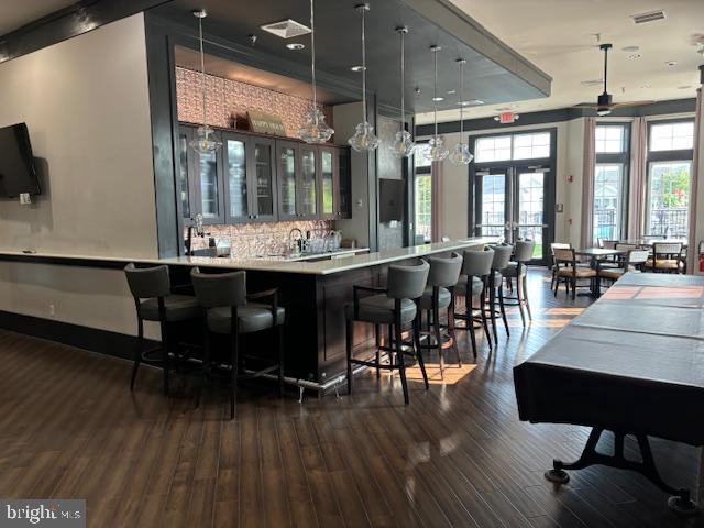 bar featuring pendant lighting, decorative backsplash, dark hardwood / wood-style flooring, and french doors