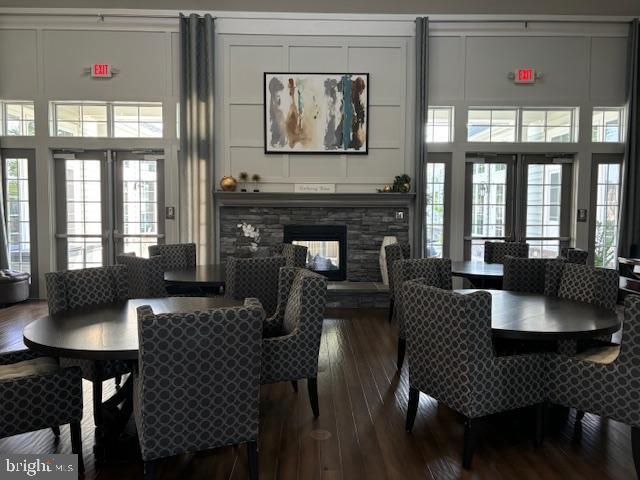 dining room featuring a stone fireplace, french doors, a high ceiling, and hardwood / wood-style flooring