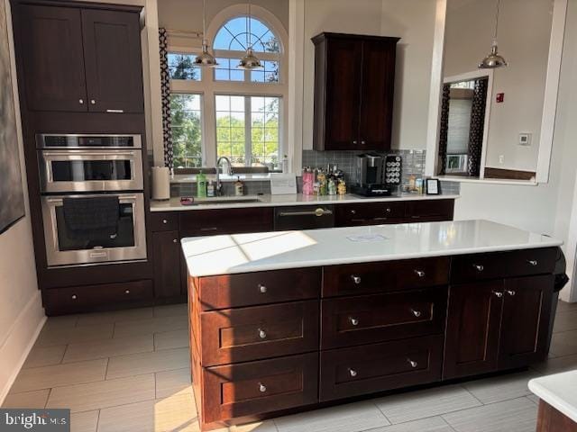 kitchen with sink, double oven, hanging light fixtures, dark brown cabinets, and tasteful backsplash