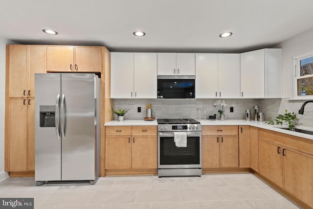 kitchen with white cabinetry, sink, stainless steel appliances, backsplash, and light brown cabinetry