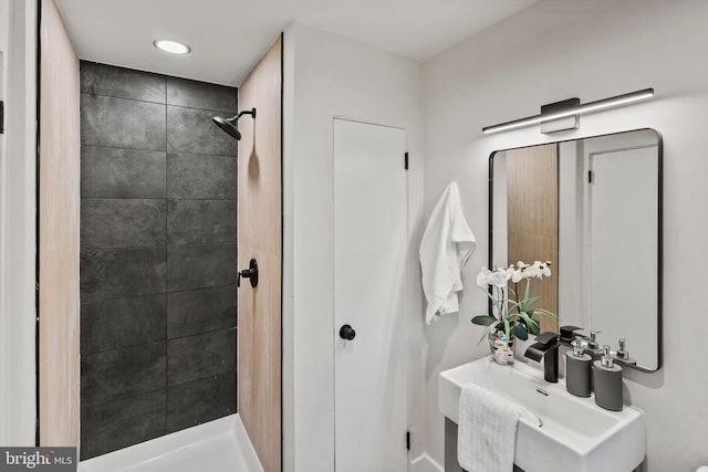 bathroom with tiled shower and sink