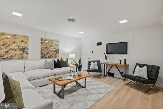 living room featuring crown molding and light hardwood / wood-style flooring