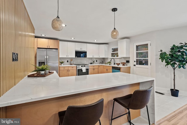 kitchen featuring white cabinets, appliances with stainless steel finishes, kitchen peninsula, and pendant lighting