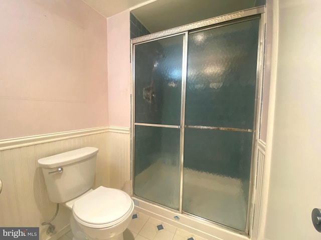 bathroom with tile patterned flooring, an enclosed shower, and toilet