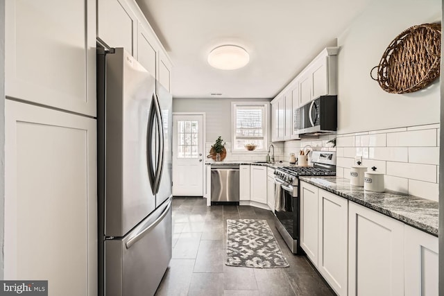 kitchen with appliances with stainless steel finishes, stone counters, white cabinetry, and a sink