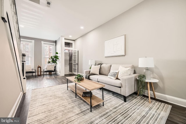 living area with recessed lighting, wood finished floors, visible vents, and baseboards