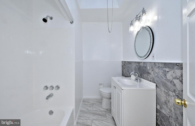 full bathroom featuring vanity, tiled shower / bath, tile walls, and toilet