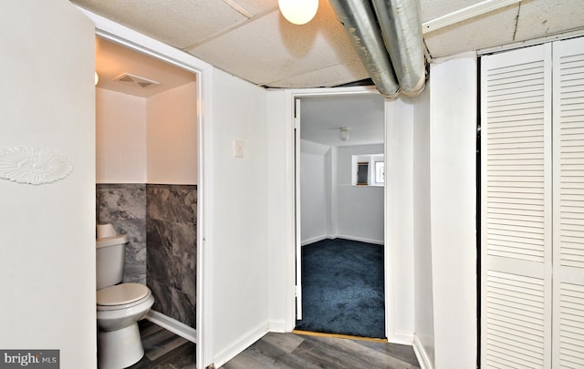 bathroom featuring hardwood / wood-style floors, tile walls, and toilet