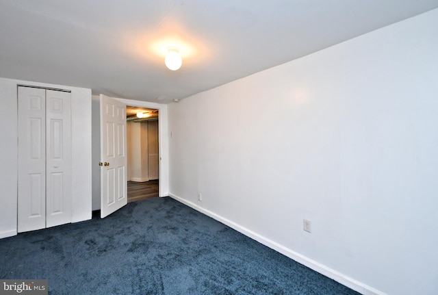 unfurnished bedroom with dark colored carpet and a closet