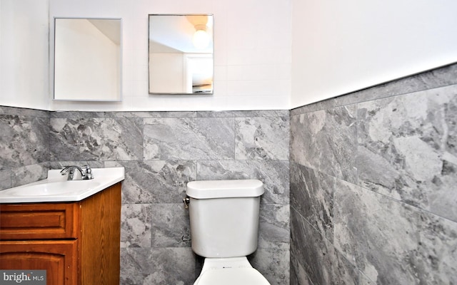 bathroom featuring vanity, tile walls, and toilet