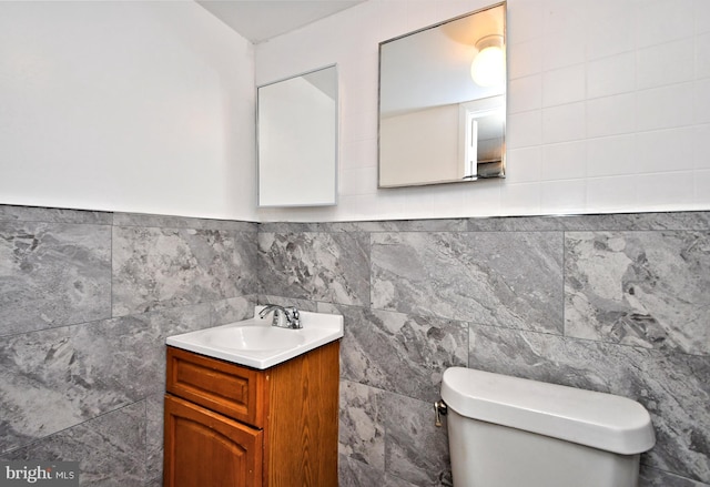 bathroom with vanity, tile walls, and toilet