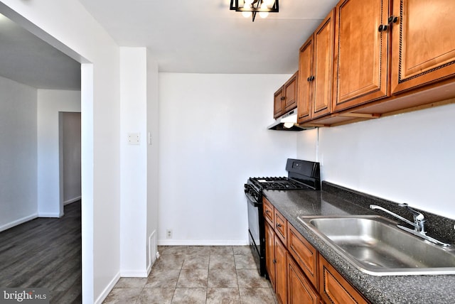 kitchen with black gas range, light tile patterned floors, exhaust hood, and sink