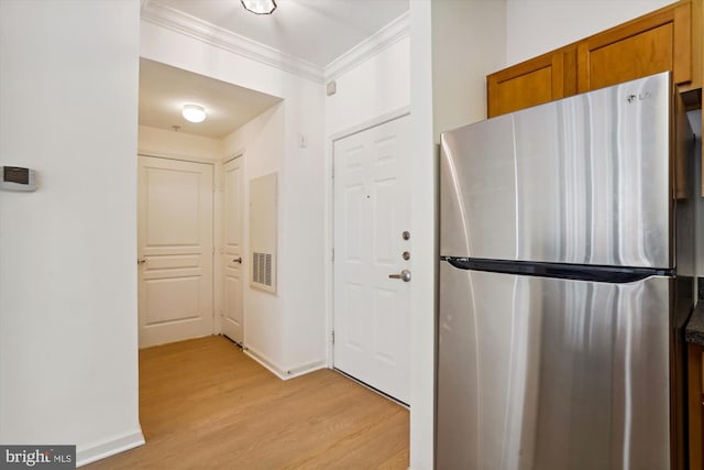 kitchen with stainless steel refrigerator, crown molding, and light hardwood / wood-style flooring