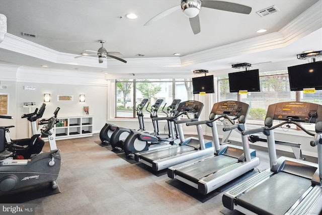 workout area featuring ceiling fan, a raised ceiling, and ornamental molding