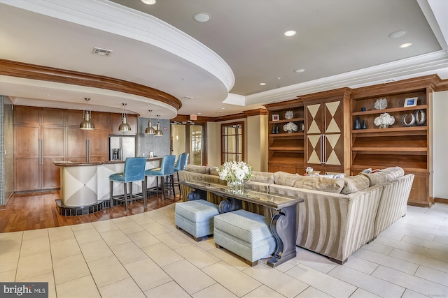 living room featuring light tile patterned flooring, ornamental molding, and a tray ceiling