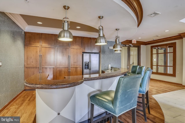 kitchen featuring stainless steel fridge, light hardwood / wood-style flooring, hanging light fixtures, and ornamental molding