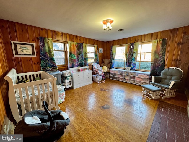 bedroom featuring a crib and wood walls