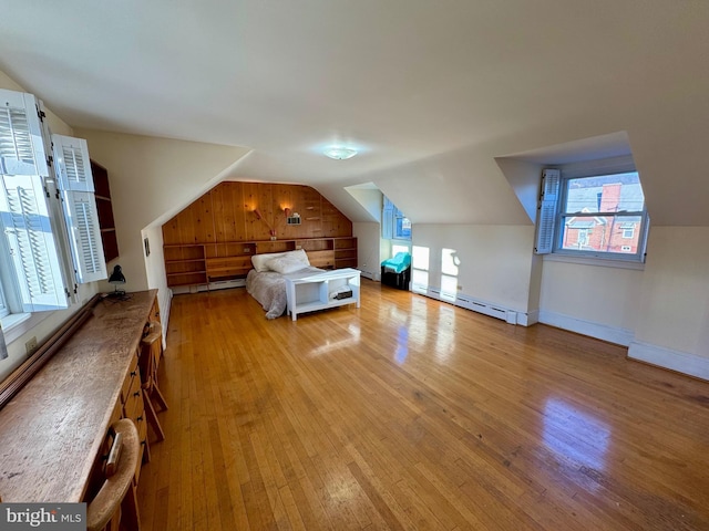 unfurnished bedroom featuring multiple windows, a baseboard radiator, lofted ceiling, and light hardwood / wood-style flooring