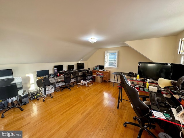 home office featuring a baseboard radiator, lofted ceiling, and hardwood / wood-style floors