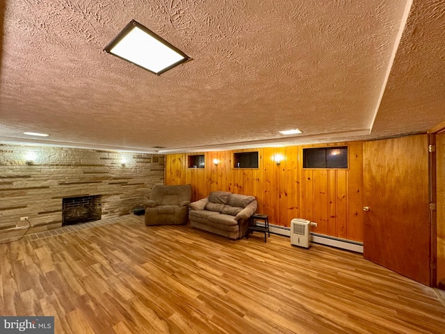 interior space with wood-type flooring, a fireplace, a textured ceiling, and baseboard heating