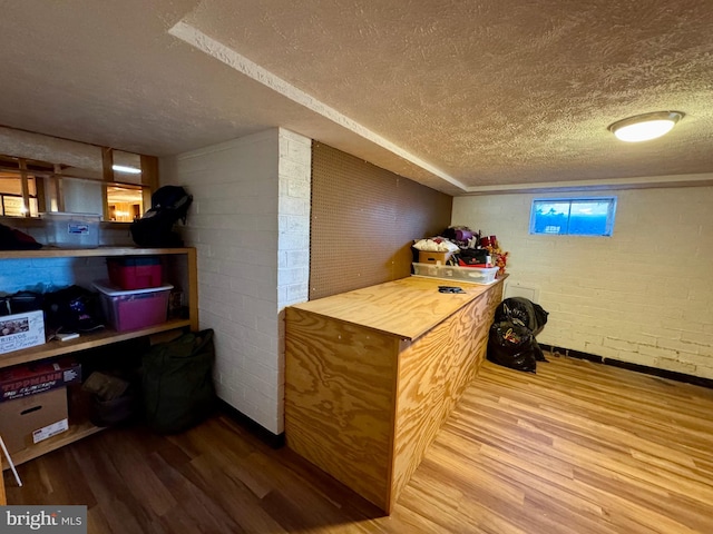 bar featuring hardwood / wood-style flooring, brick wall, and a textured ceiling