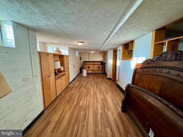 hallway featuring brick wall, a textured ceiling, and light wood-type flooring