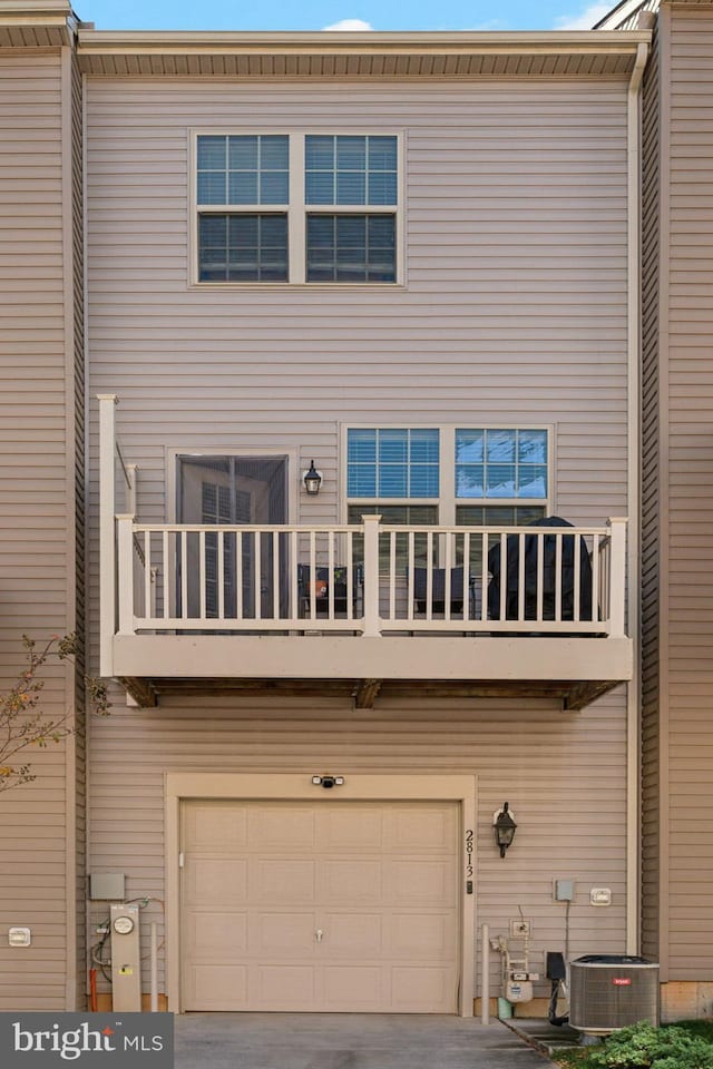 back of house featuring central AC unit, a garage, and a balcony