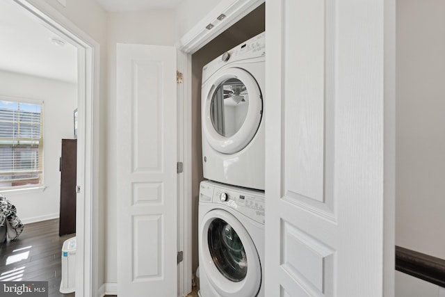 clothes washing area featuring stacked washer / drying machine and hardwood / wood-style flooring