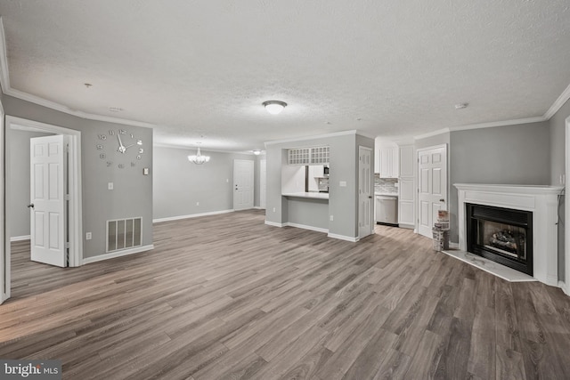 unfurnished living room featuring an inviting chandelier, wood-type flooring, a textured ceiling, and ornamental molding