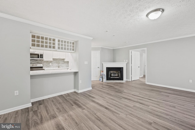 unfurnished living room with a textured ceiling, hardwood / wood-style flooring, and ornamental molding